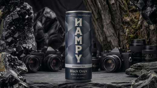 A black can of HAMPY energy drink centered against a dark marble background with subtle blue and white light highlights.