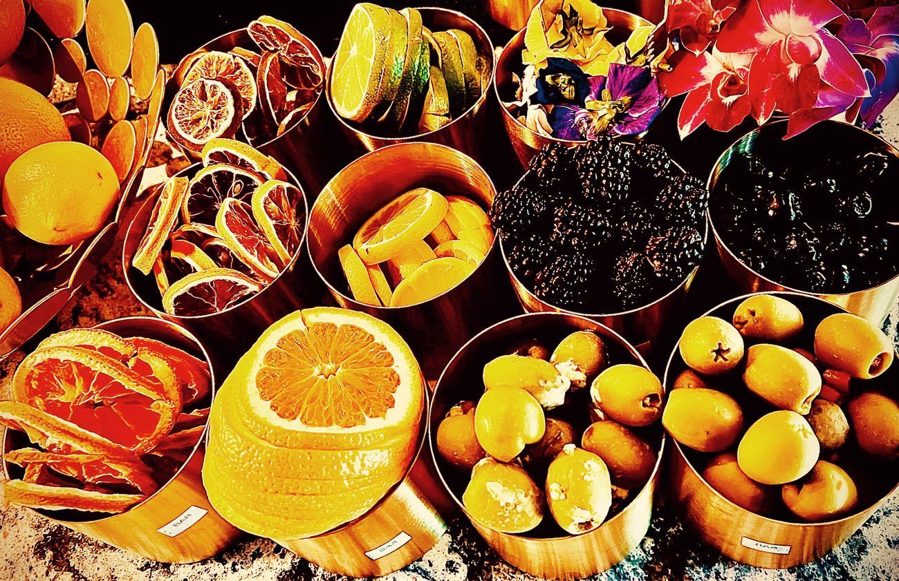 Assortment of fruit in small wooden bowls: sliced oranges, dried fruit, citrus peels, and small yellow fruit.
