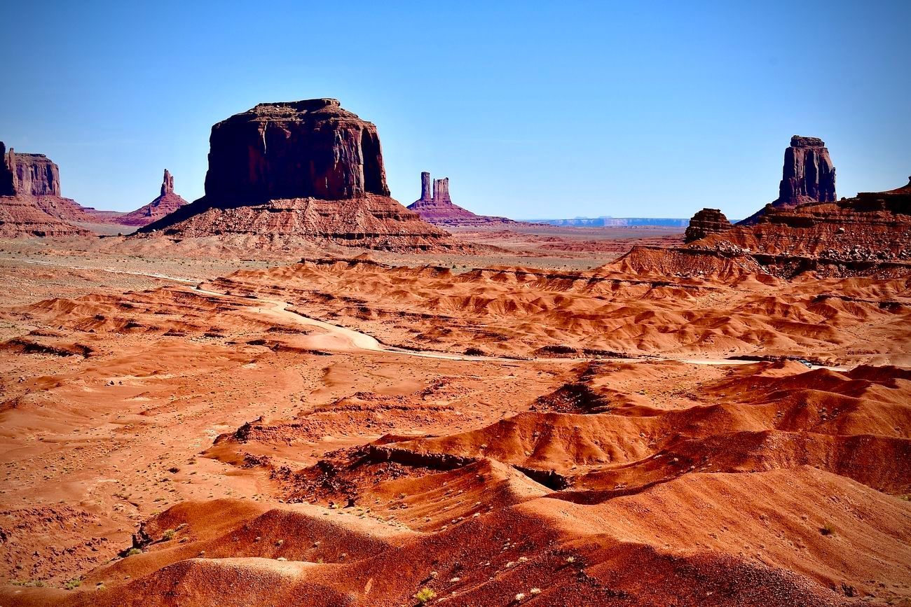 Red-rock desert landscape with sandstone buttes under a blue sky.
