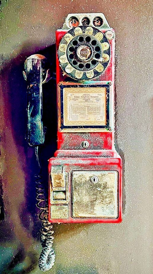 Red vintage rotary payphone mounted on a wall.