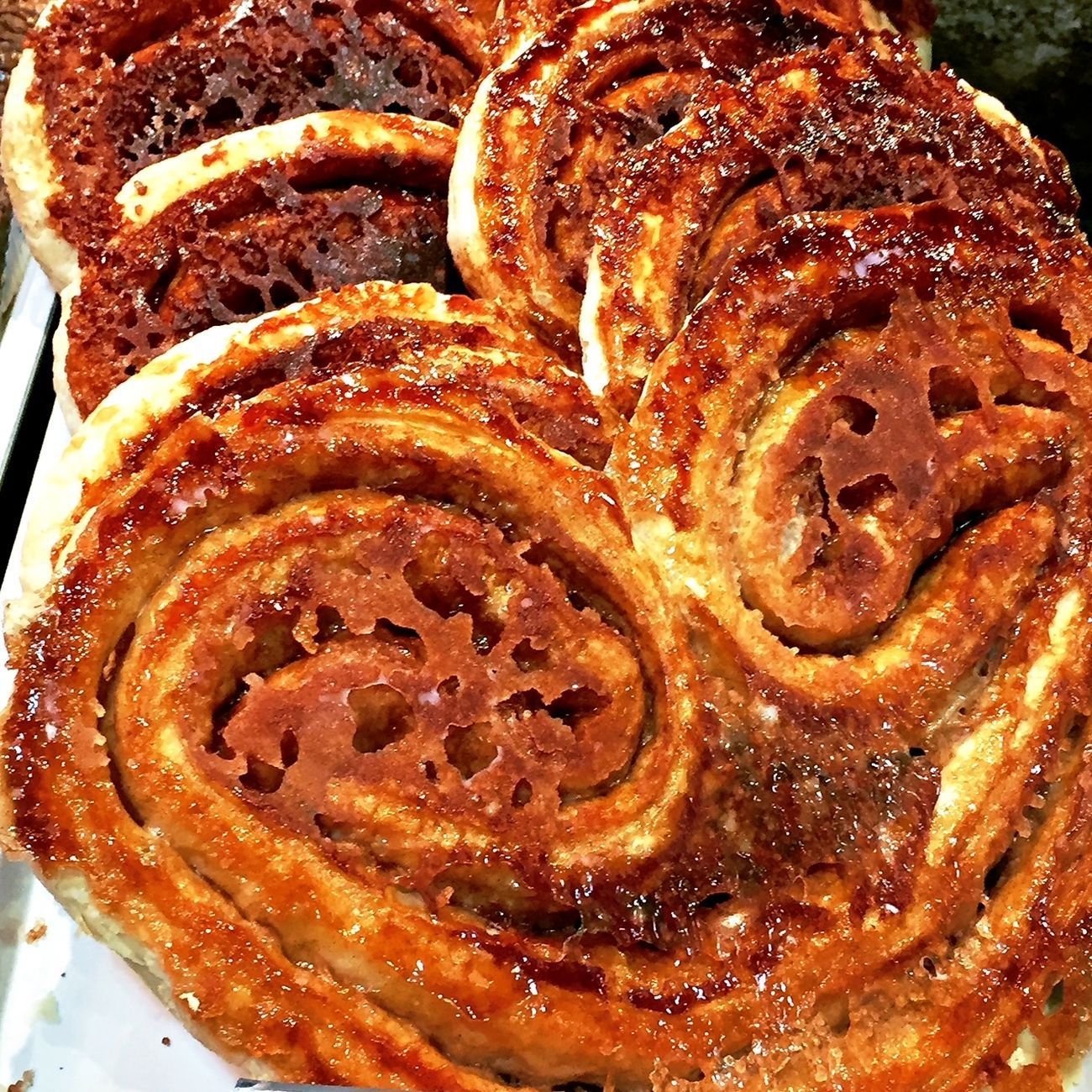 Close-up of several baked, spiral-shaped pastries with caramelized sugar glaze.