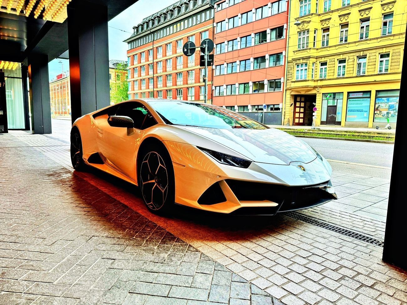 White Lamborghini parked on a city street, buildings in the background.