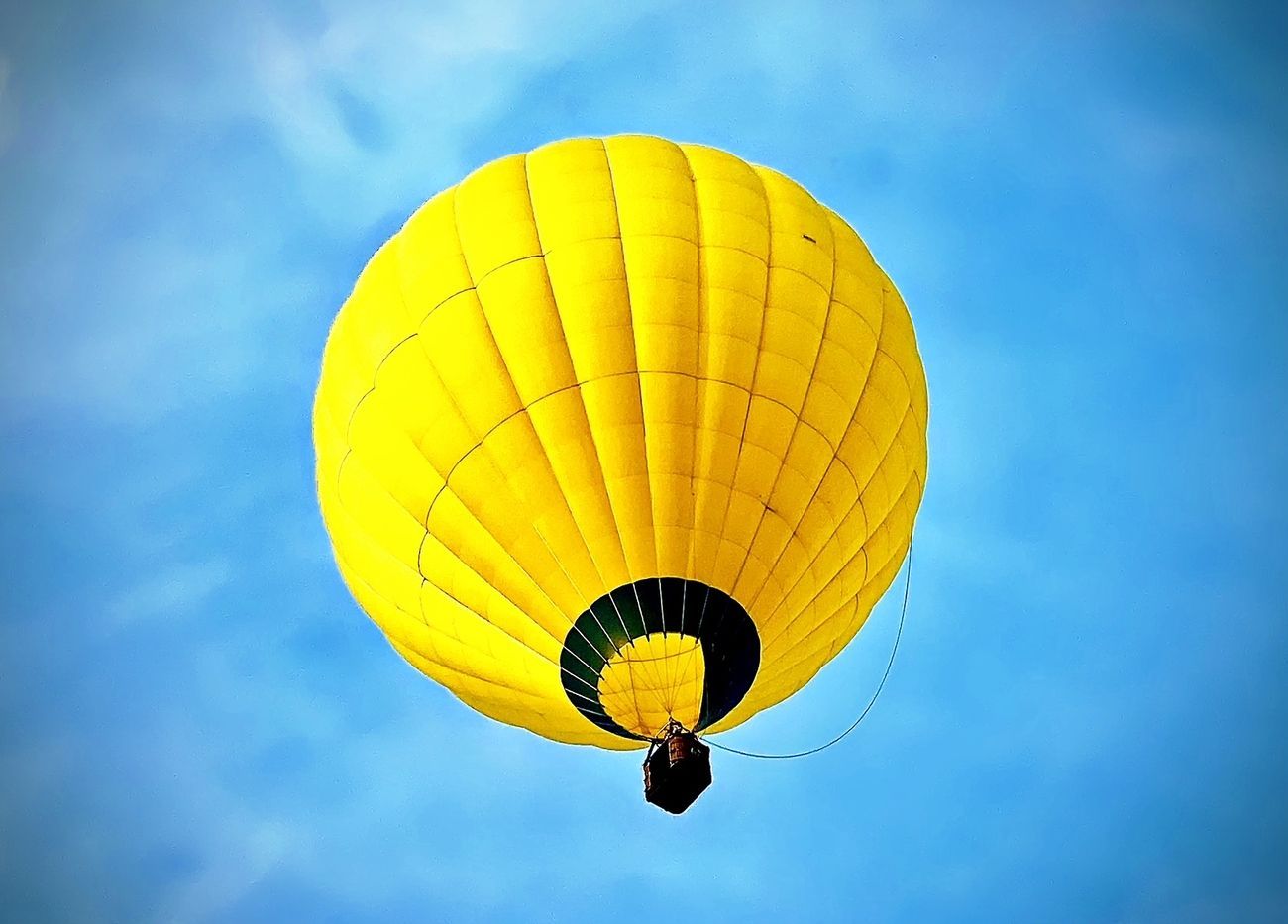 Yellow hot air balloon against a blue sky.
