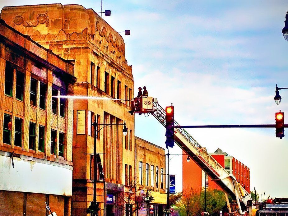 Firefighters on an aerial ladder spraying water onto a building, downtown.