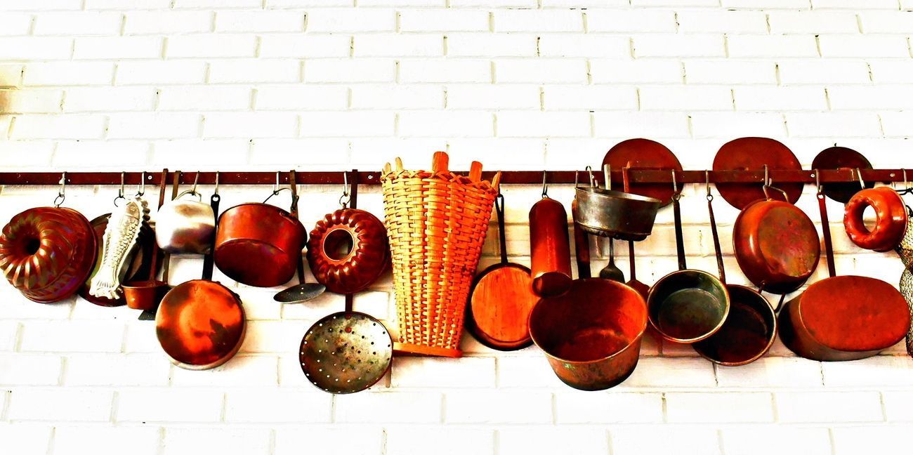 Pots and pans hanging on a rack against a white brick wall.