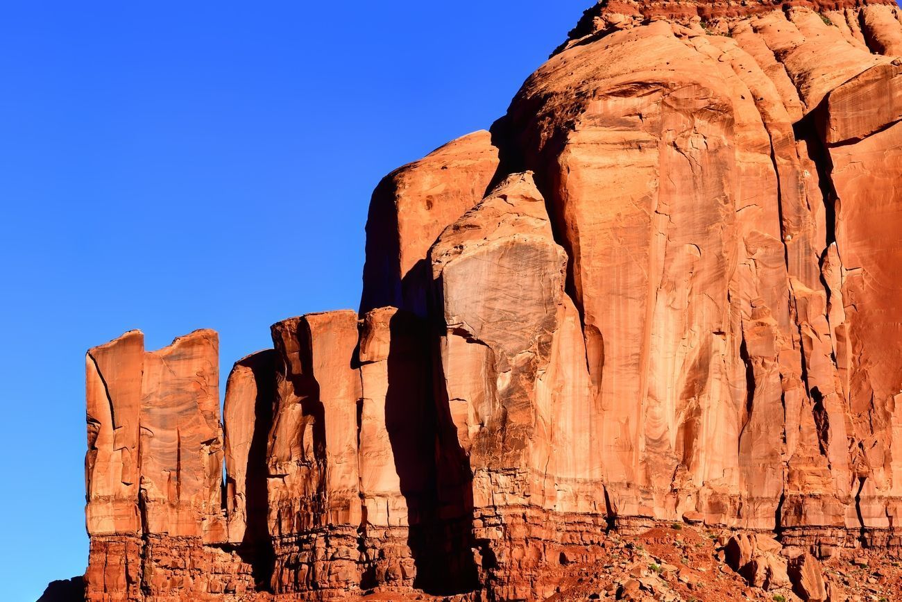 Red sandstone cliffs against a clear blue sky, likely in a desert landscape.