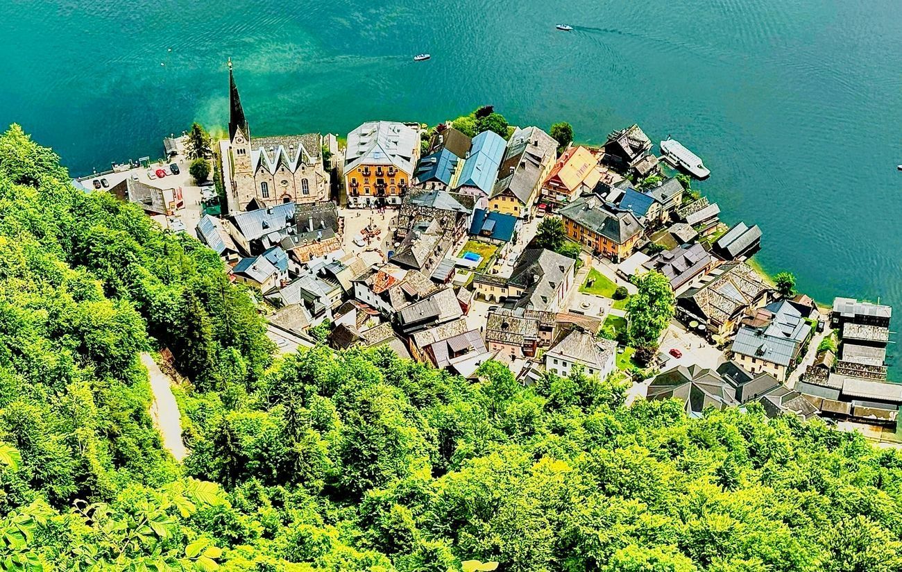 Aerial view of Hallstatt, Austria, nestled beside a lake and surrounded by green hills.