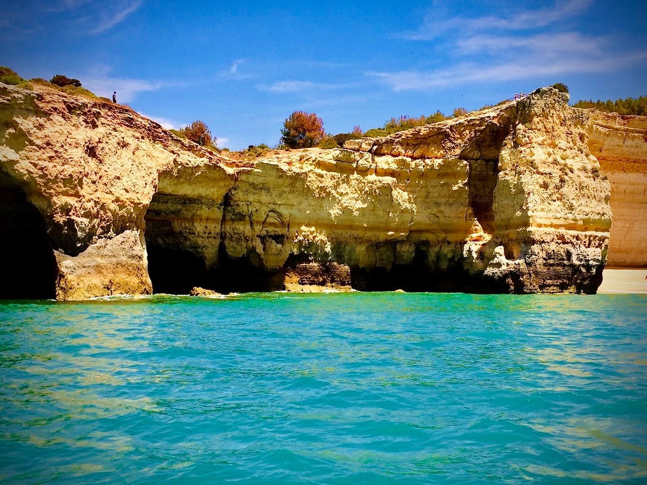 Cliffs with caves over turquoise water on a sunny day.
