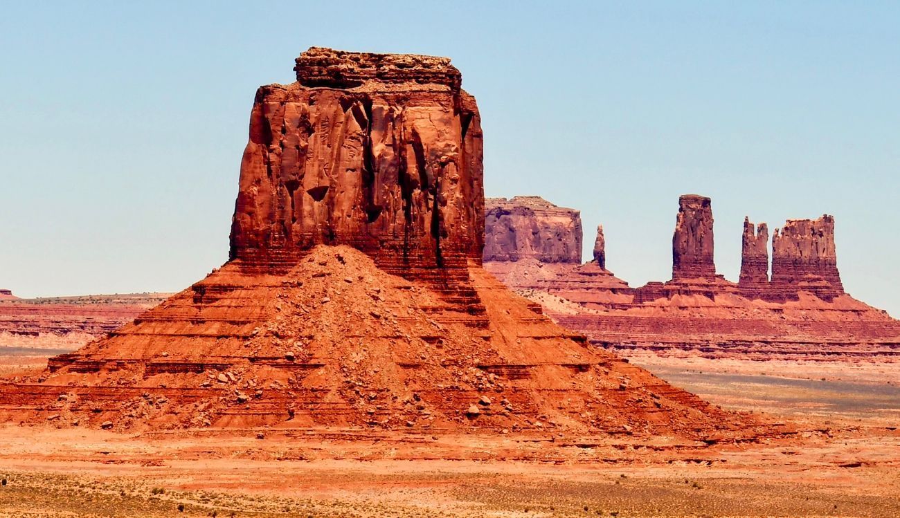 Red sandstone buttes in Monument Valley, Utah, under a clear blue sky.