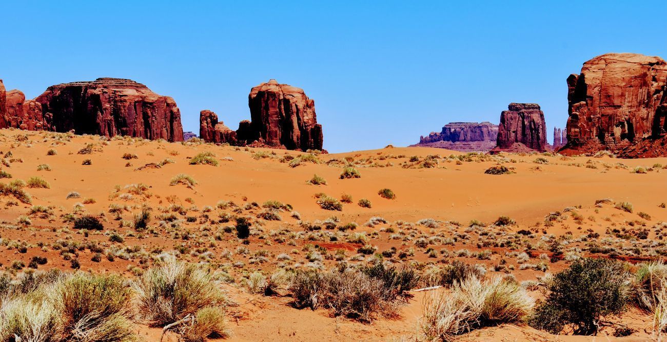Desert landscape with red rock formations and blue sky.