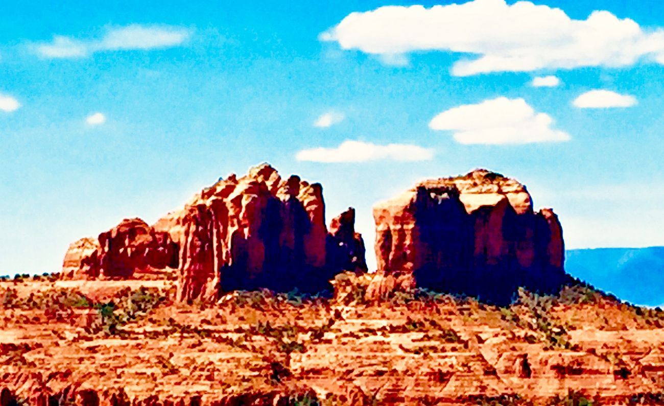Red rock formations under a blue sky with scattered clouds, Southwestern landscape.