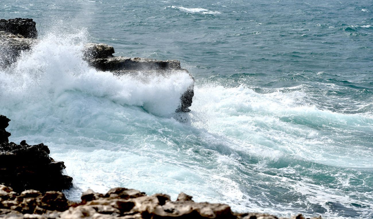 Ocean waves crashing against rocky shoreline, creating white spray.