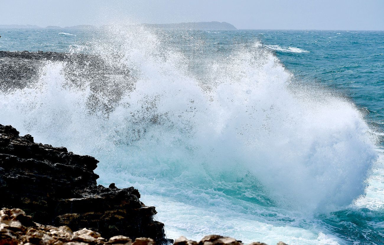 Ocean waves crashing against rocky shoreline, creating white spray.