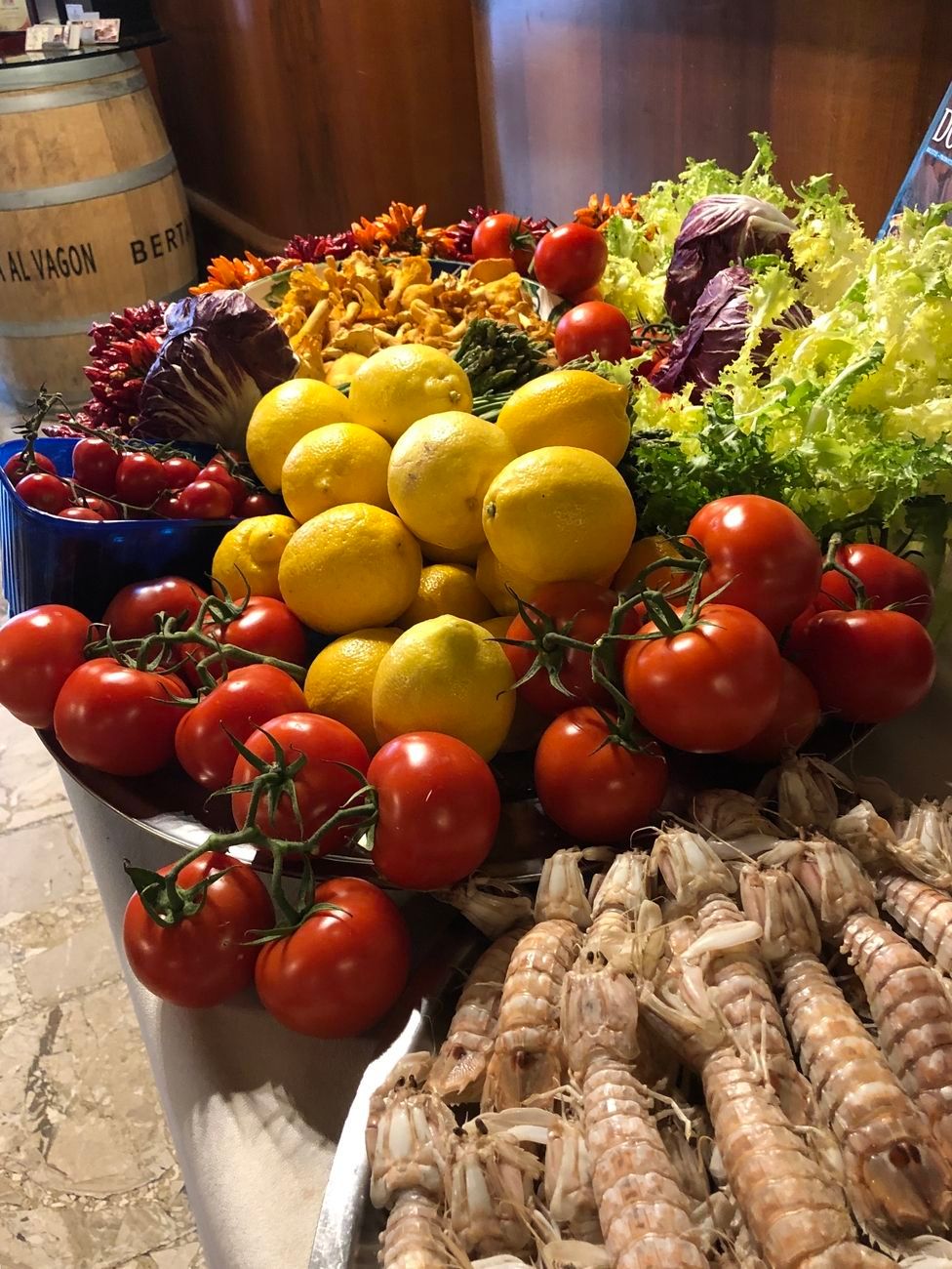 Tomatoes, lemons, lettuce, pasta, and shrimp arranged on a table.