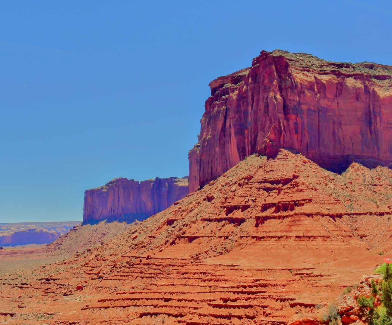 Red rock formations in desert landscape under a clear blue sky.