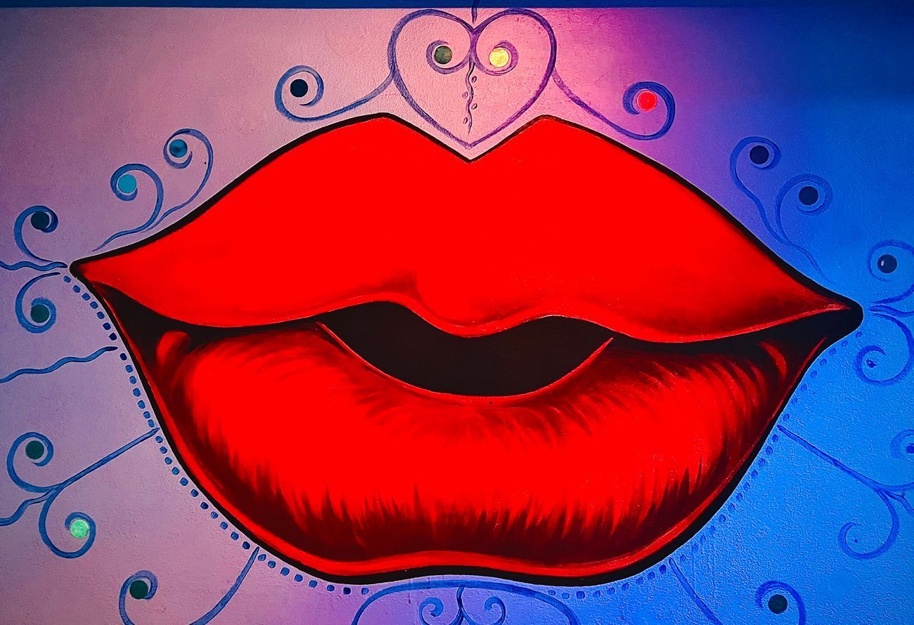 Red lips artwork on a blue background, adorned with decorative swirls and a heart.