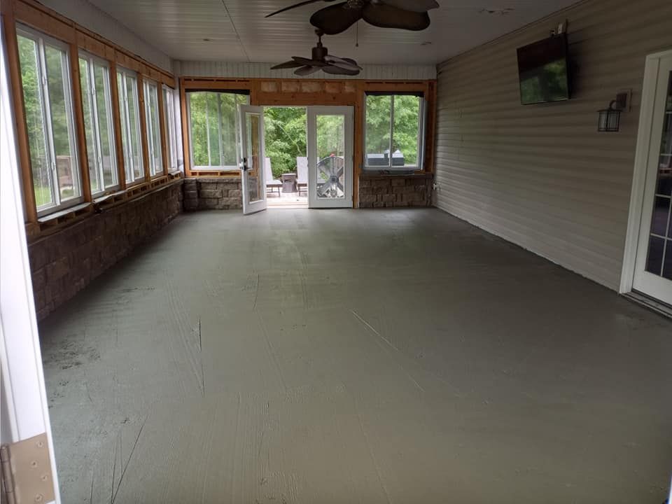 Spacious screened-in porch with a gray concrete floor, large windows, ceiling fans, and an open double-door exit.
