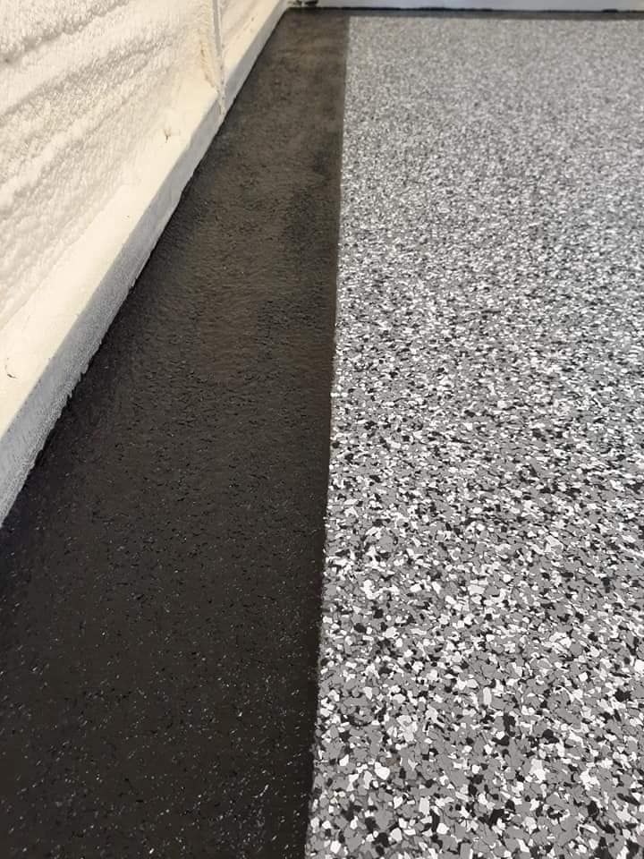 A floor split between a solid dark gray textured edge and a gray and white speckled epoxy finish.
