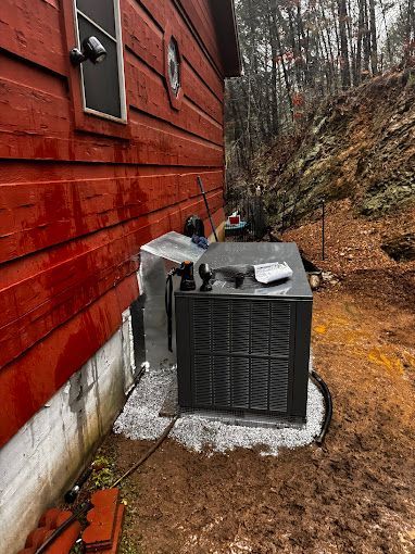 An air conditioner is sitting on the side of a red house.