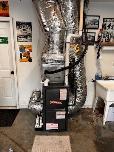 A furnace is sitting in a garage next to a sink.