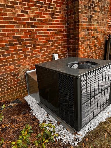 A large air conditioner is sitting outside of a brick building.