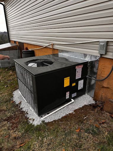 A black air conditioner is sitting on the side of a house.