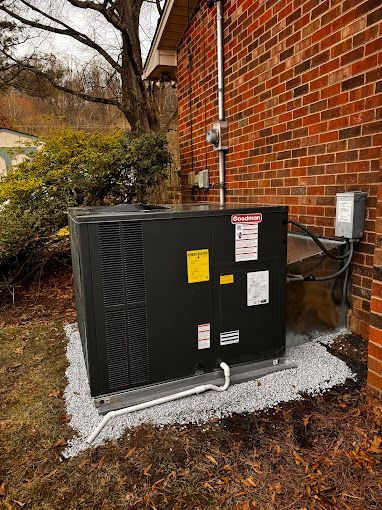 A black air conditioner is sitting on the side of a brick building.