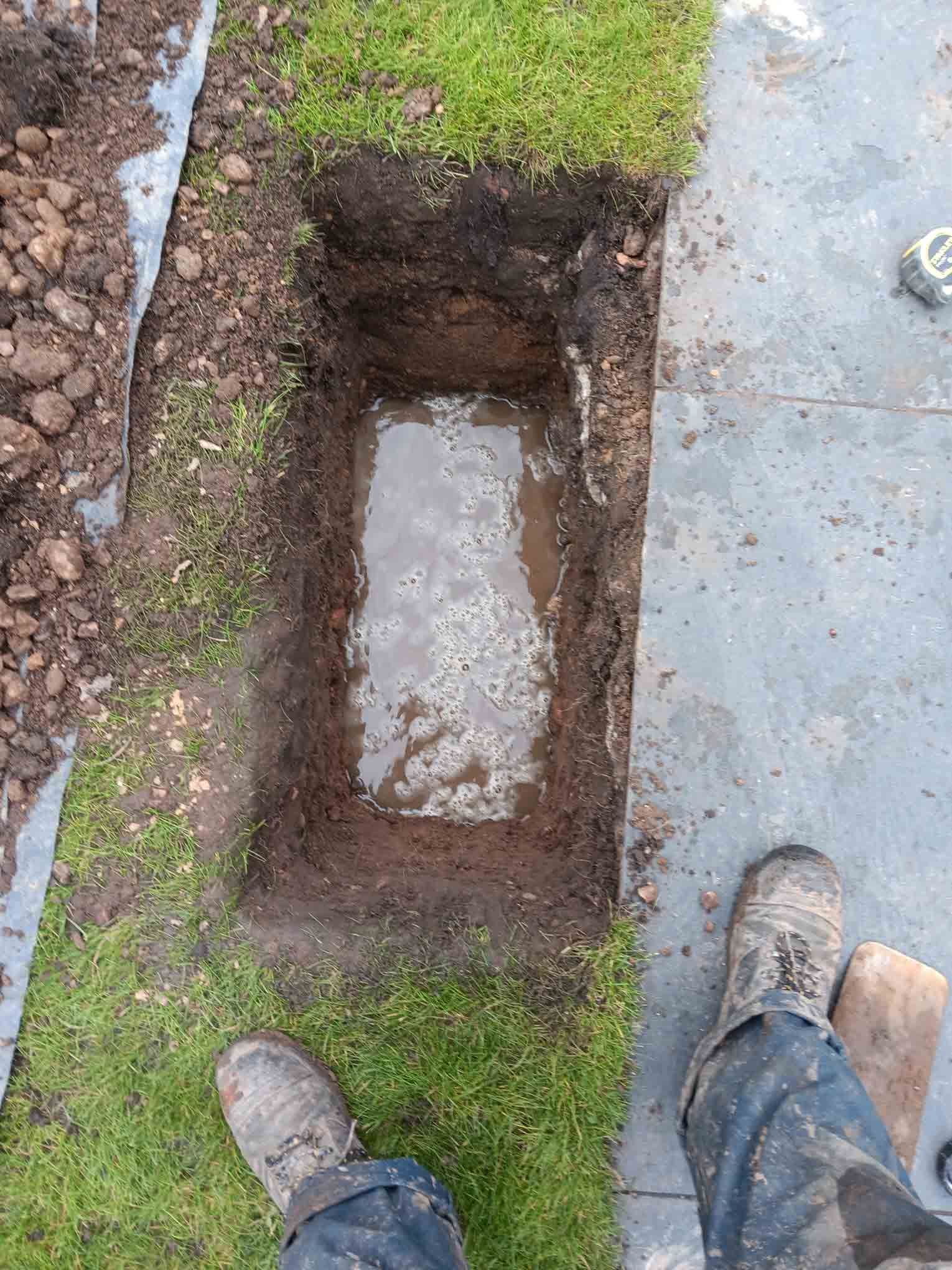 ditch in a lawn with water at the bottom
