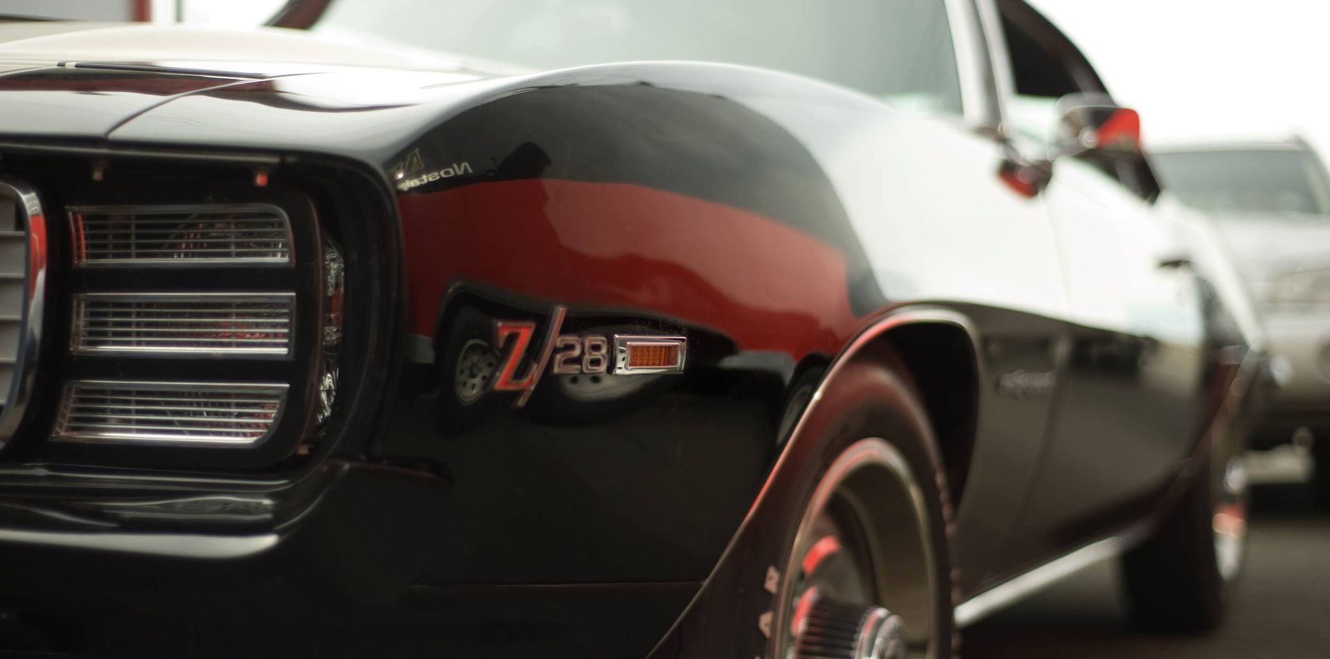 A black and red muscle car is parked on the side of the road.