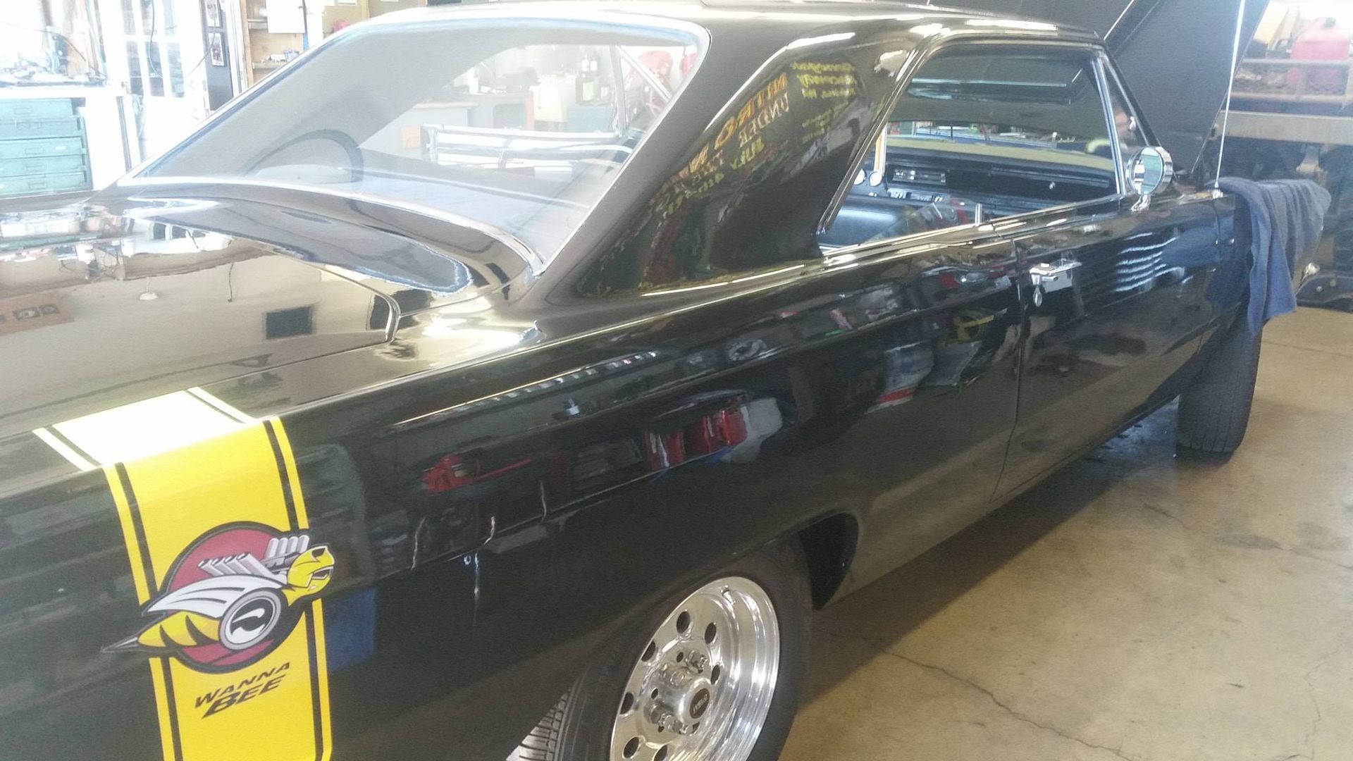 A black car with a yellow stripe on the side is parked in a garage.