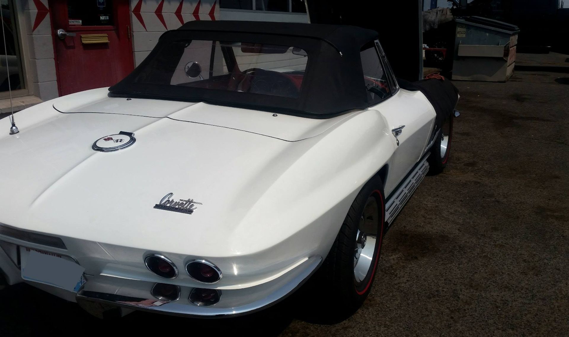 A white corvette is parked in front of a building
