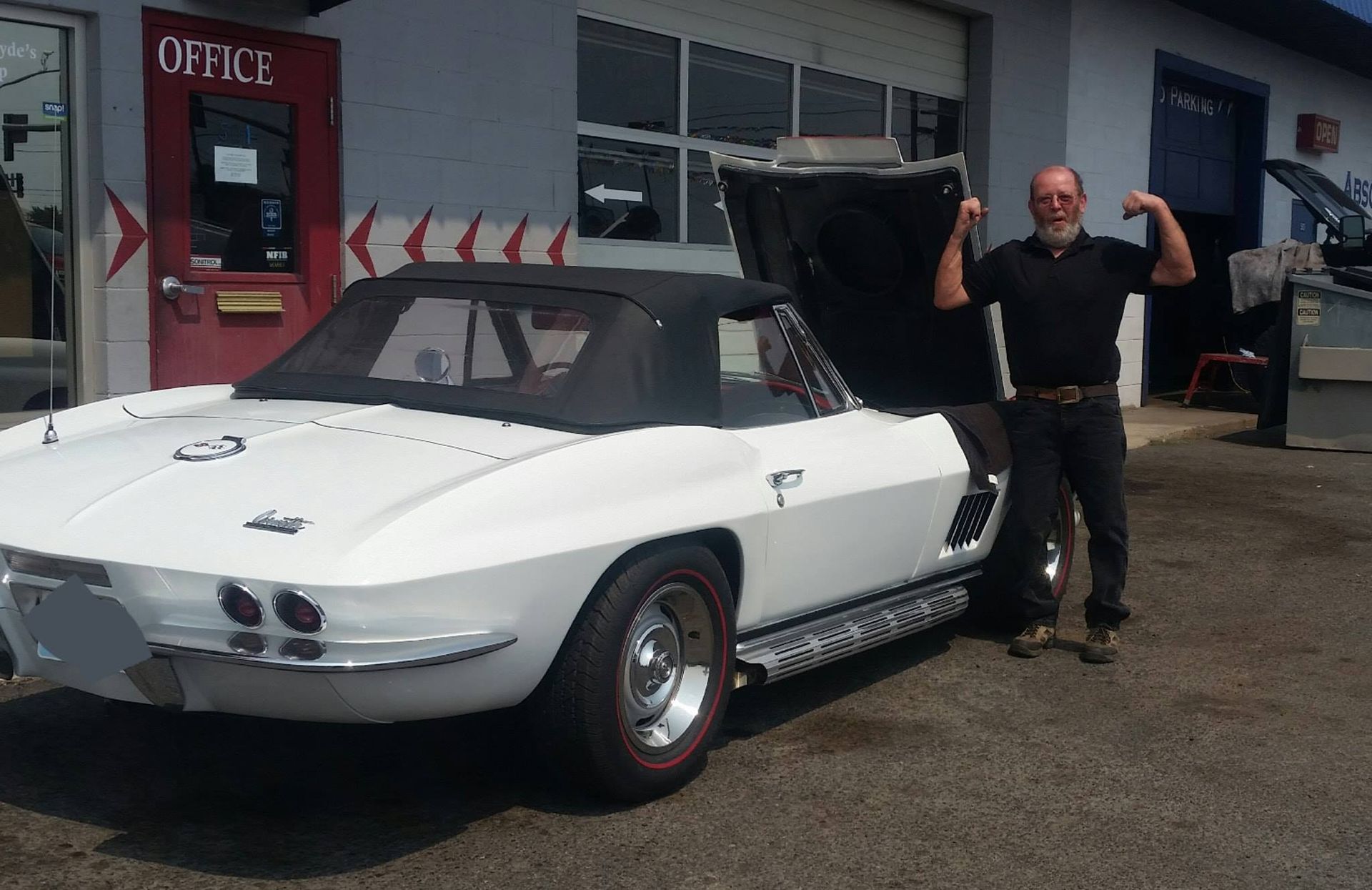A man is standing in front of a white car with the hood open