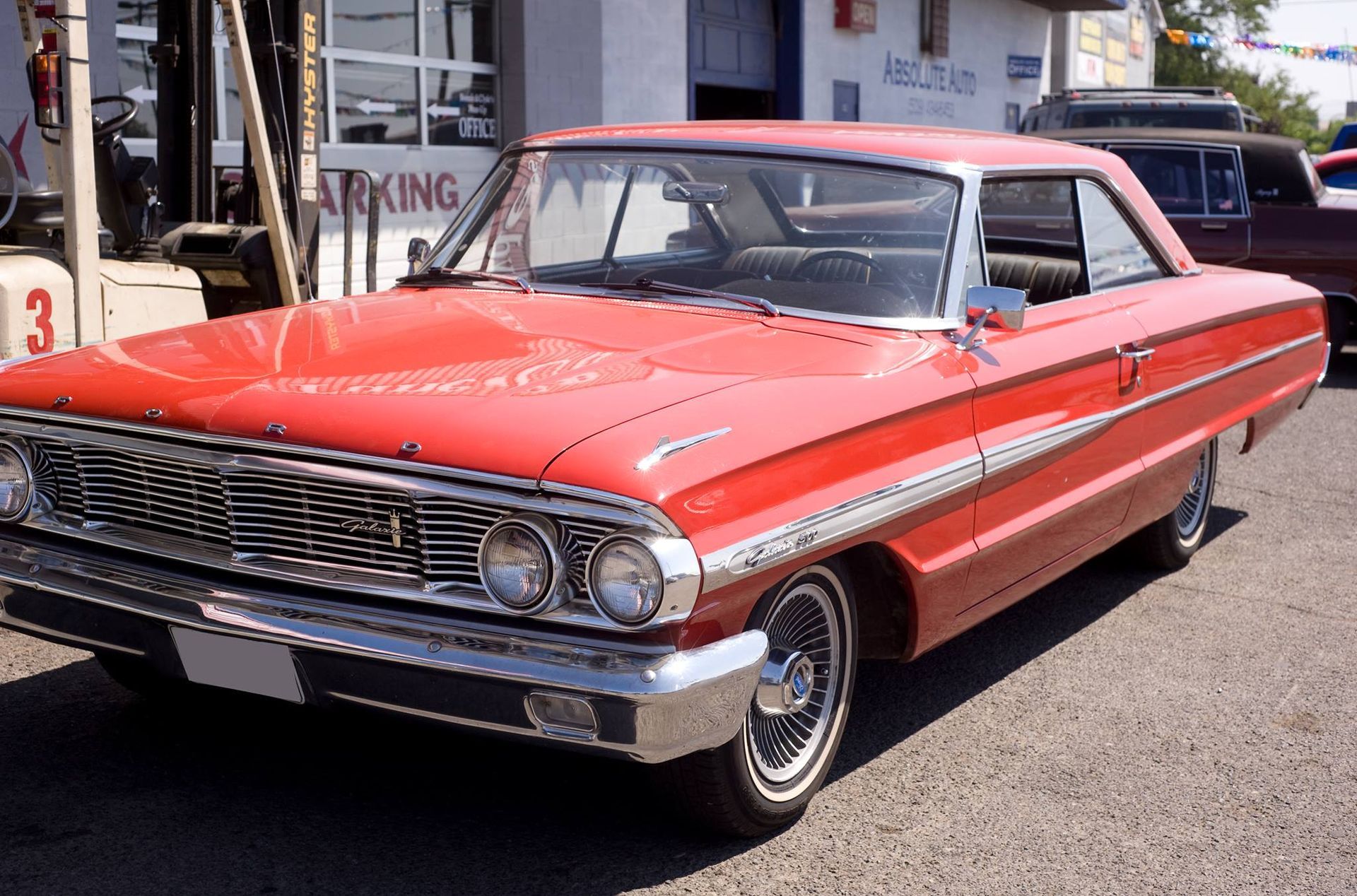 A red car is parked in front of a building that says towing