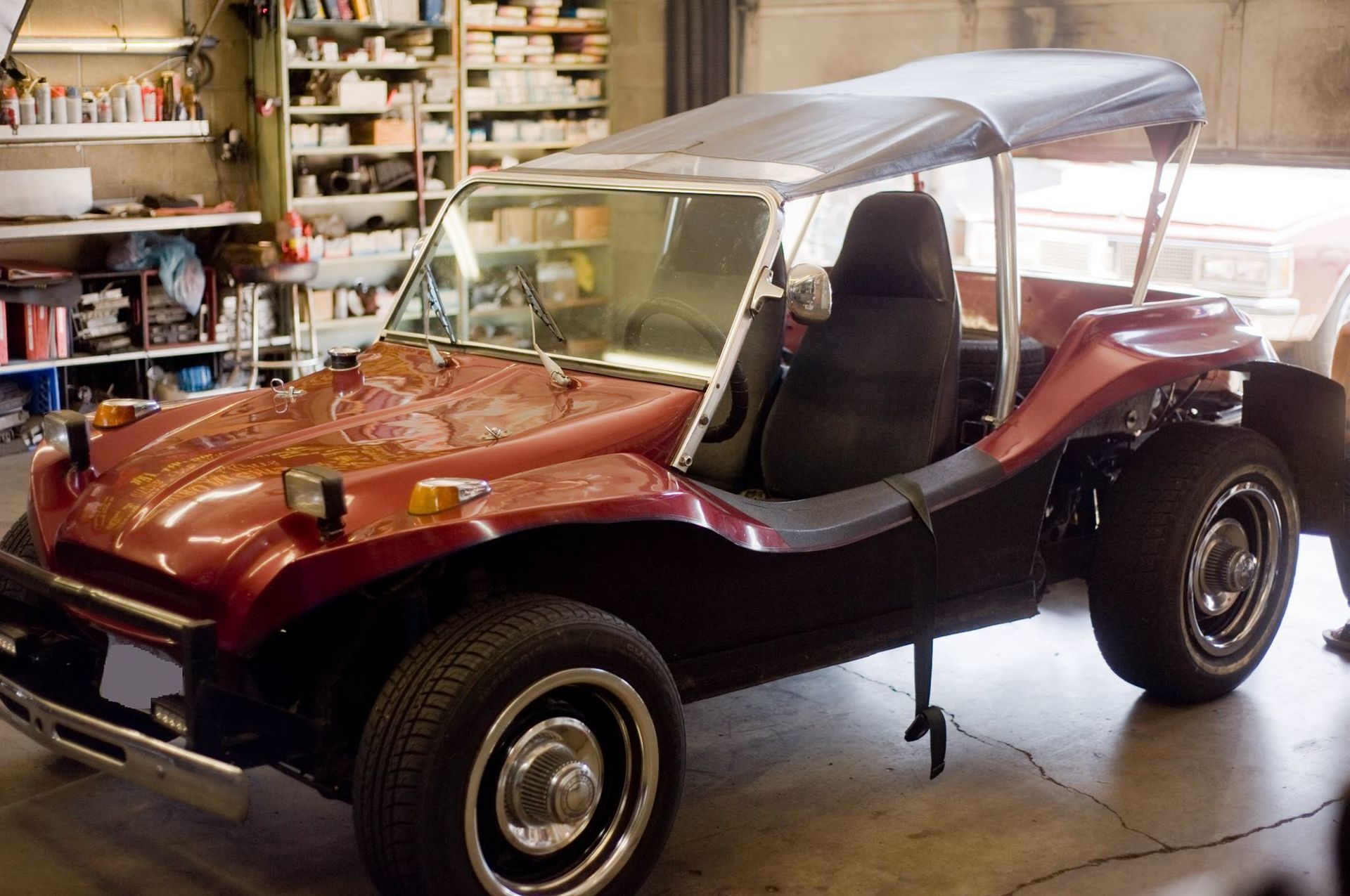 A red dune buggy is parked in a garage