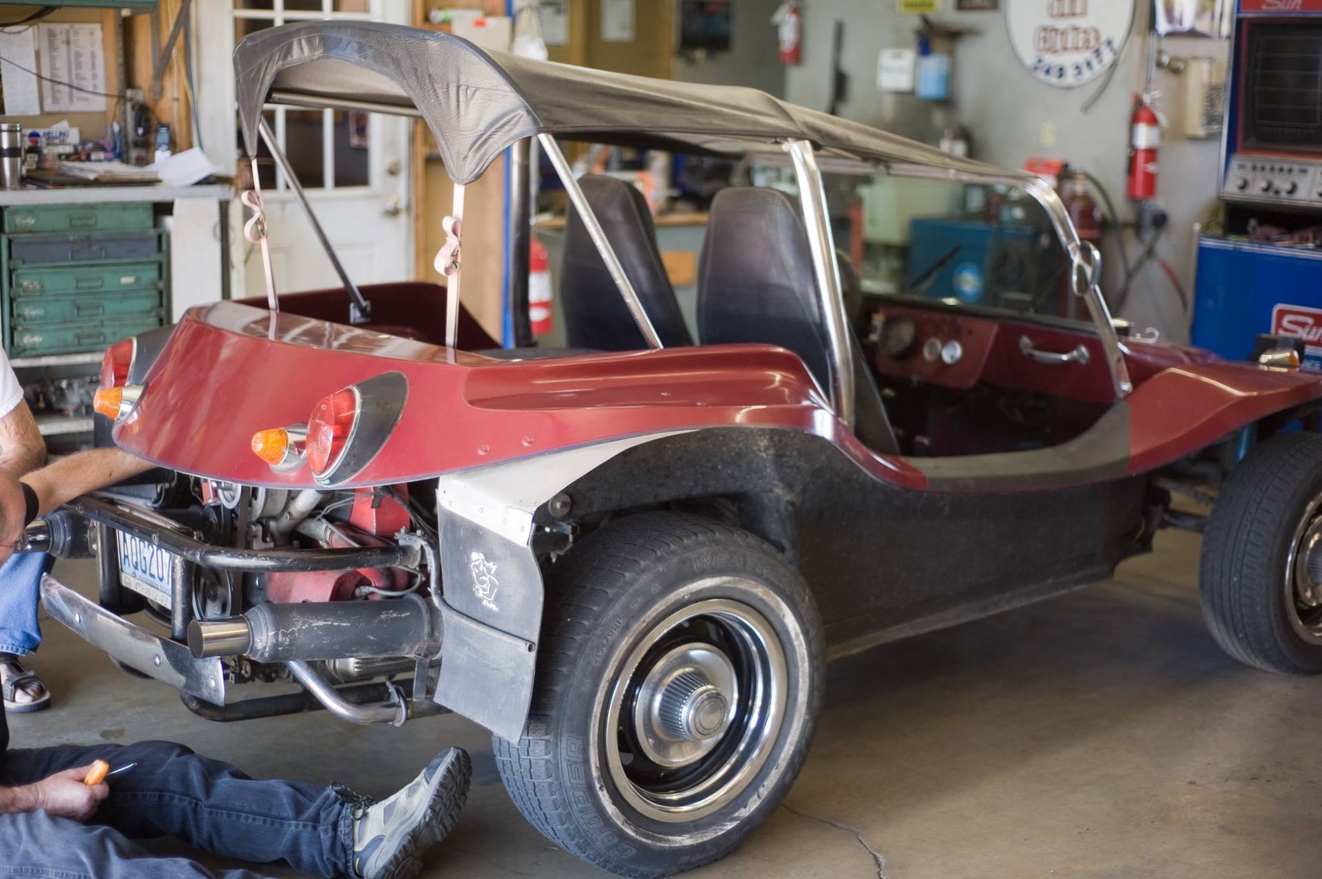 A man is working on a red buggy in a garage