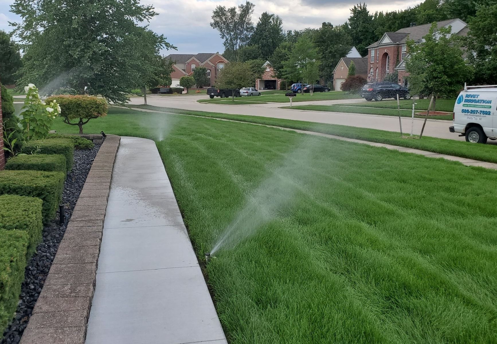 A lawn sprinkler is spraying water on a lush green lawn.