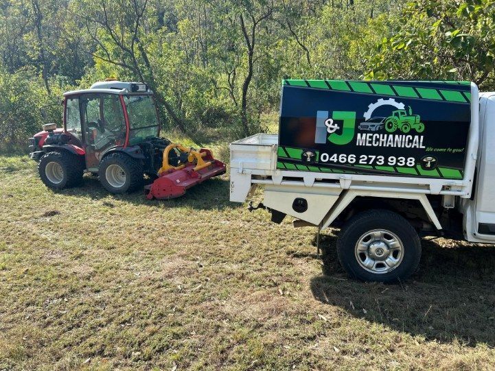 A Red Tractor With a Mower Attachment Next to a White Truck — I & J Mechanical in Deeragun, QLD