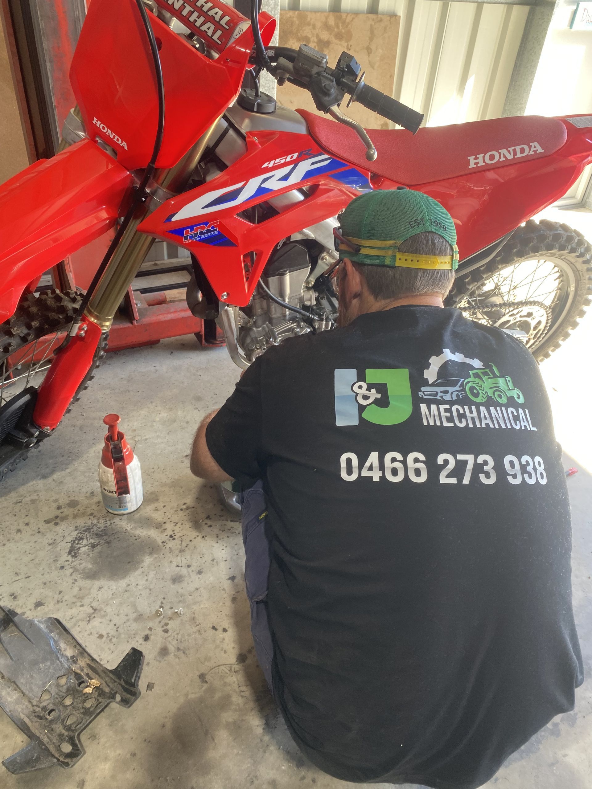 Person Working on A Red Honda Bike — I & J Mechanical in Deeragun, QLD