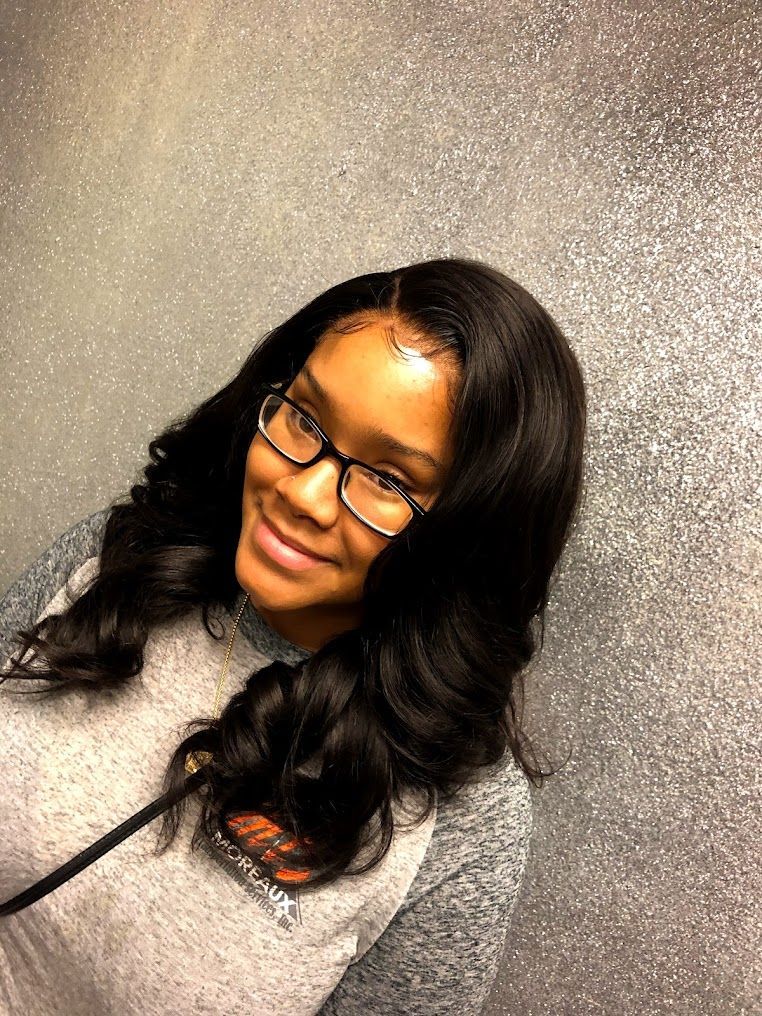 A woman wearing glasses and a gray shirt is smiling.