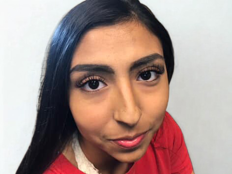 A woman in a purple dress with a plunging neckline is smiling.