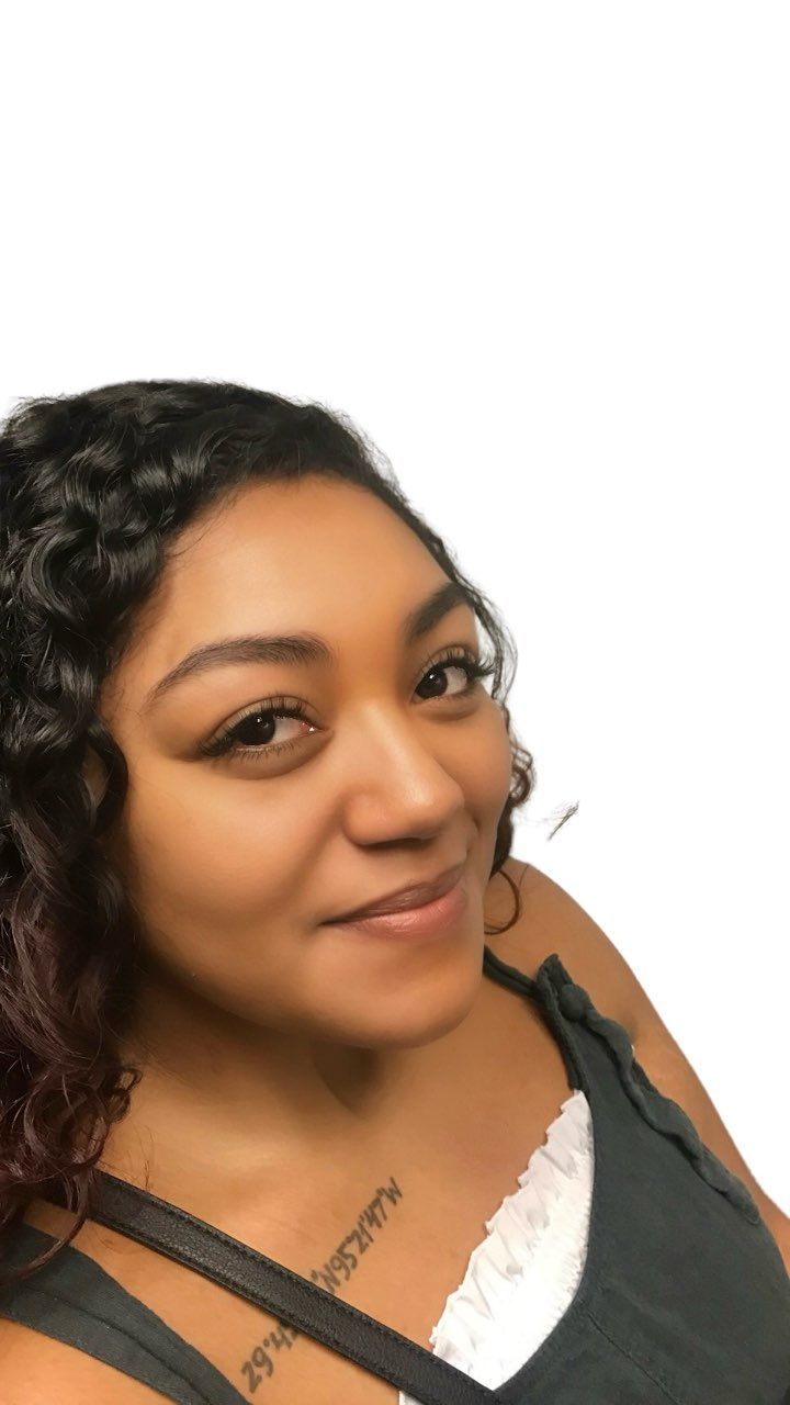 A woman wearing a bun and earrings looks over her shoulder