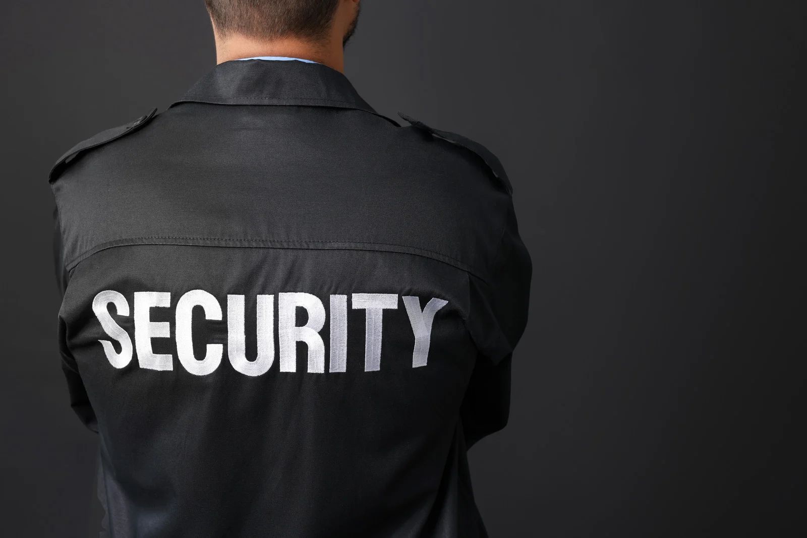 Back of a security guard wearing a black uniform with