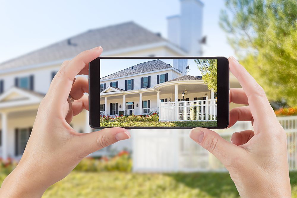A person is taking a picture of a house with a cell phone.