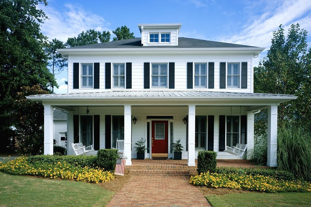 A white house with black shutters and a red door