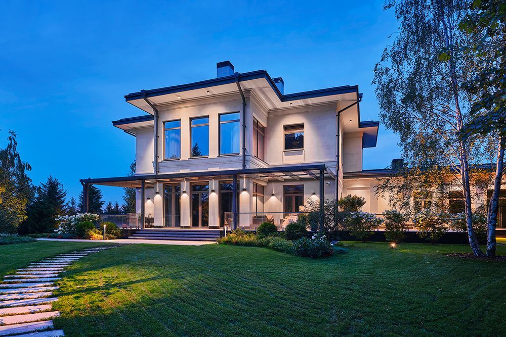A large house with a lot of windows is lit up at night.