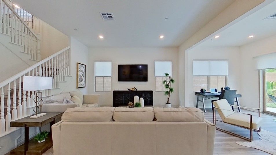 A living room with a couch, chair, television and stairs