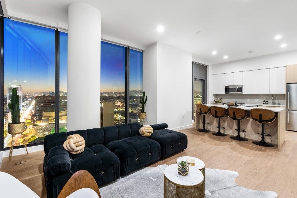 A living room with a black couch and a view of the city