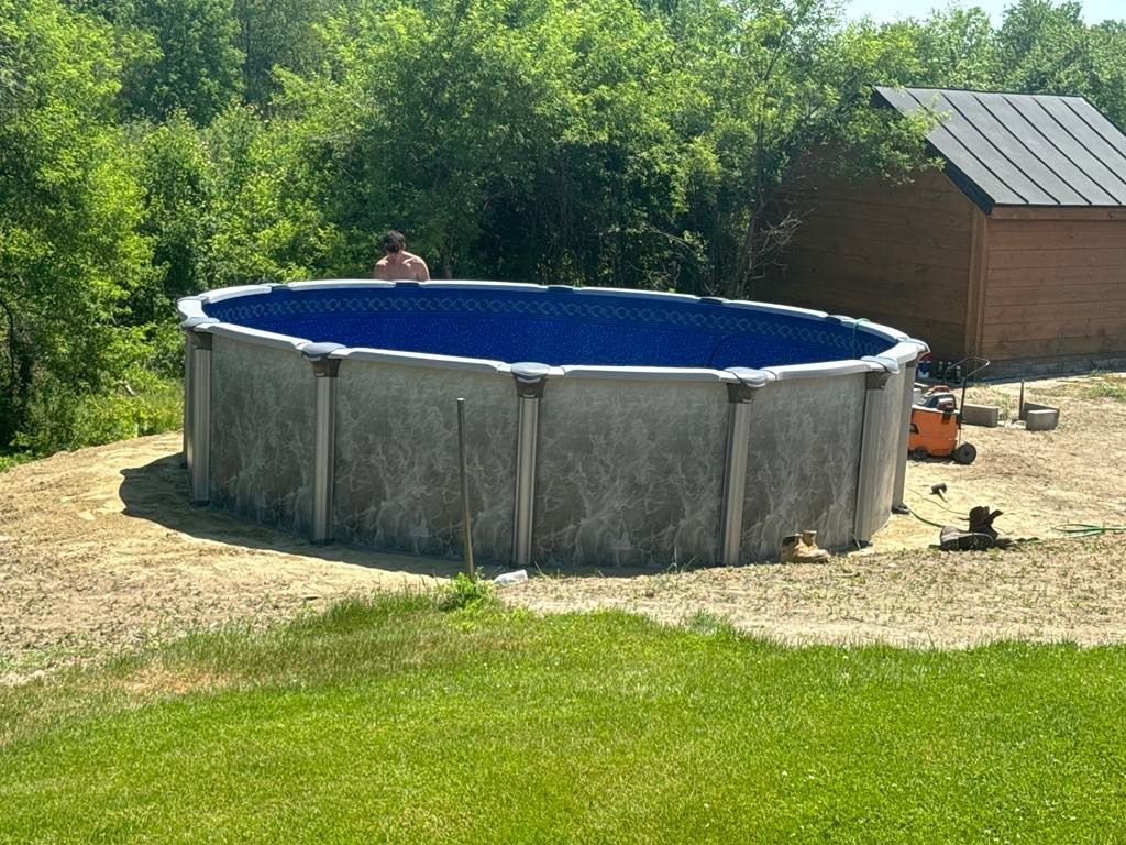 A large swimming pool is sitting in the middle of a lush green field.