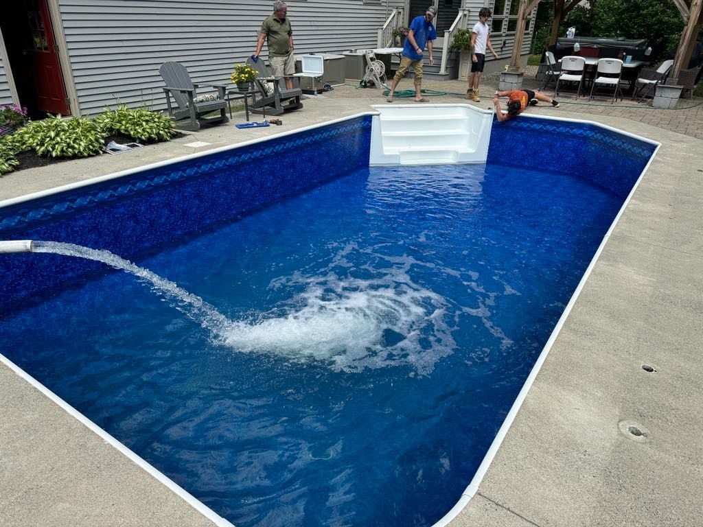 A hose is spraying water into a large swimming pool.