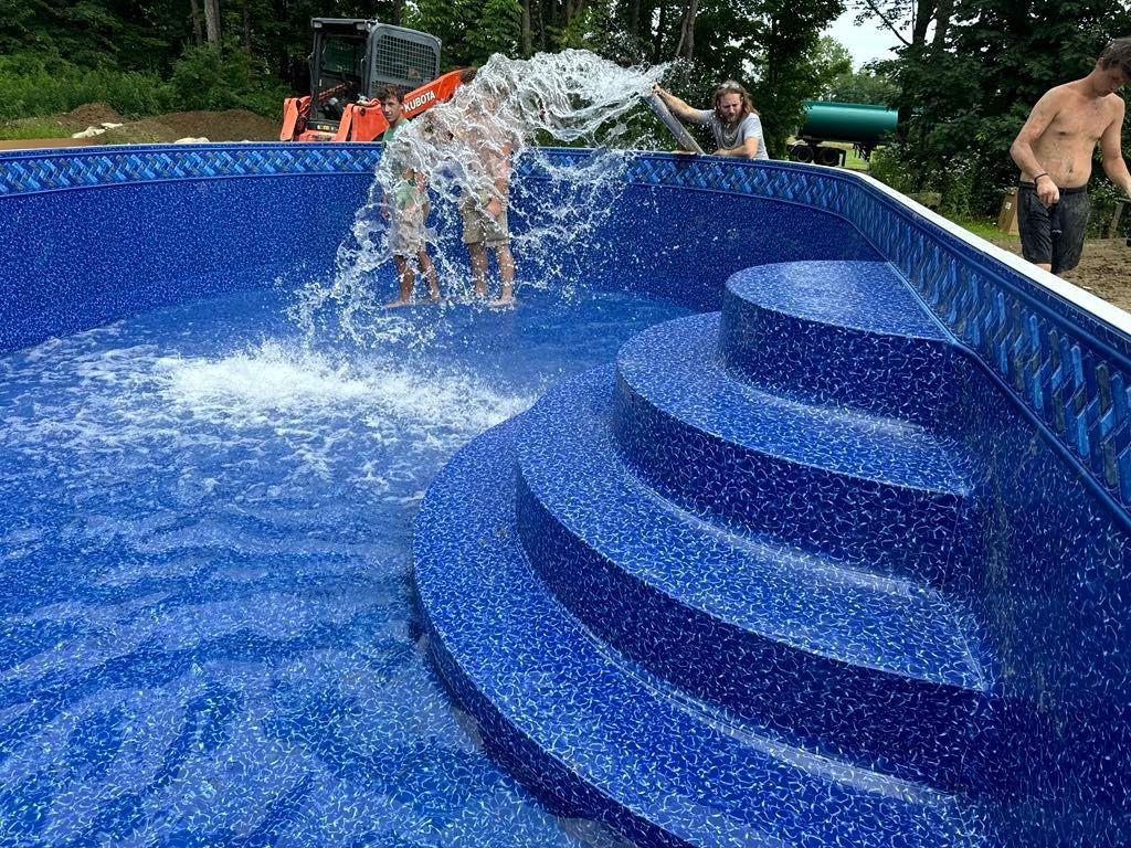A man is pouring water into a swimming pool with stairs.